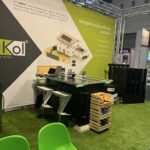 Messestand von AluKol® mit Tisch, Broschüren und dekorativen Elementen.