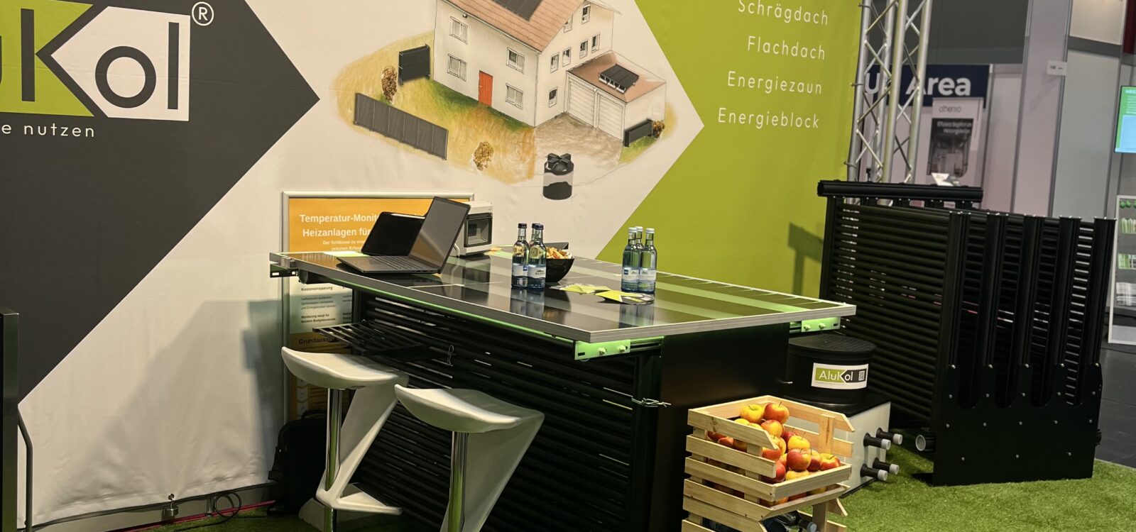 Messestand von AluKol® mit Tisch, Broschüren und dekorativen Elementen.