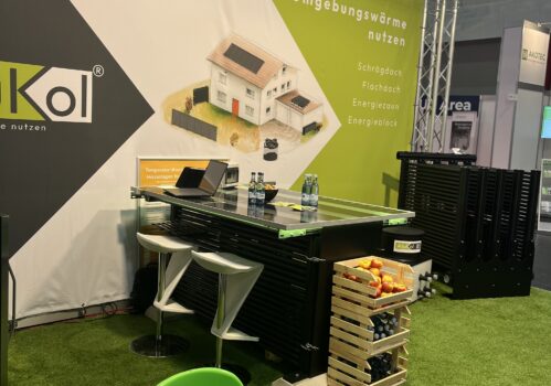 Messestand von AluKol® mit Tisch, Broschüren und dekorativen Elementen.