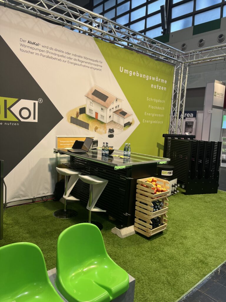 Messestand von AluKol® mit Tisch, Broschüren und dekorativen Elementen.